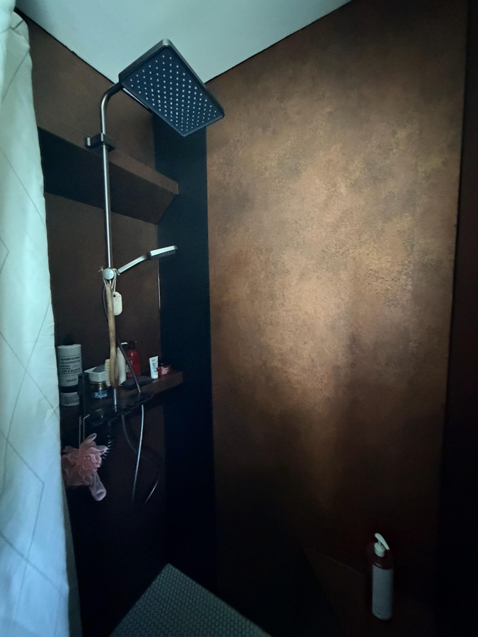Transformation complète de cette douche avec la pose de plaques de Dibond pour créer une surface parfaitement lisse et régulière. Les parois ont ensuite été habillées d’un revêtement architectural effet cuivre, associé à un noir mat pour apporter du contraste et un style résolument moderne. Une rénovation sur mesure réalisée sans démolition complète de l’existant. ReStyle réalise vos projets de rénovation et de covering architectural à Thionville, en Moselle, au Luxembourg et dans toute la région Grand Est. - après